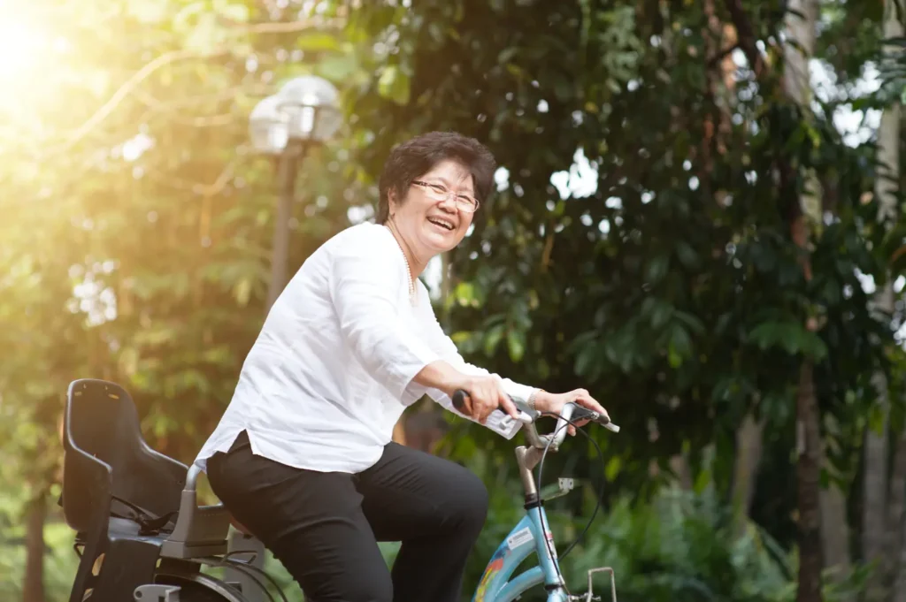 ผู้สูงอายุหญิงขี่จักรยานในสวน