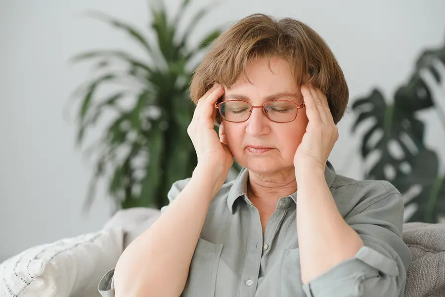 ผู้สูงอายุนั่งหลับตาใช้สองมือนวดบริเวณขมับสองข้าง ช่วยให้สมองทำงานสมดุล